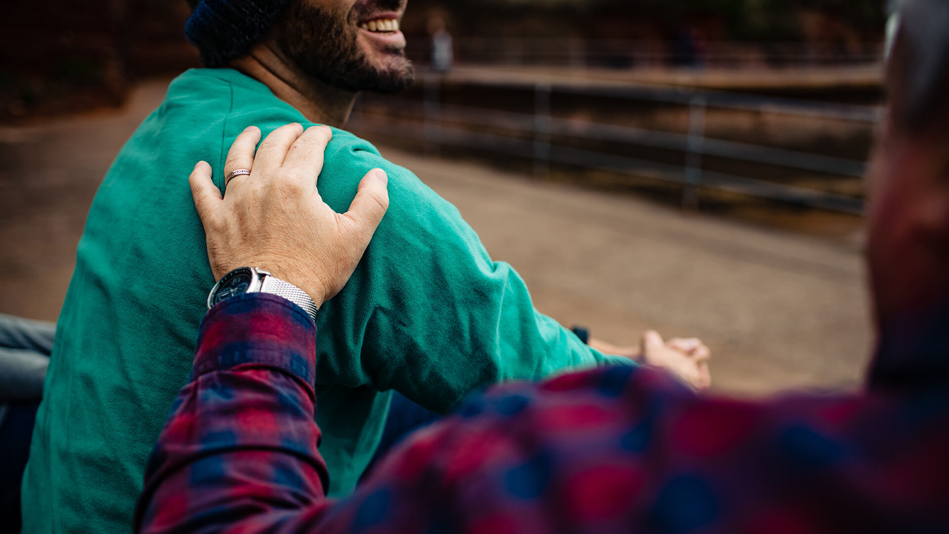 A friend of family member has his hand on the shoulder of another man who looks comforted as they discuss mental health.