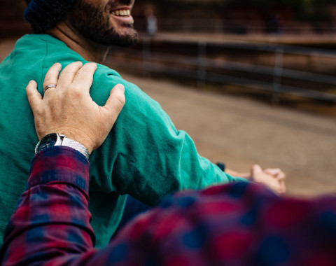 A friend of family member has his hand on the shoulder of another man who looks comforted as they discuss mental health.