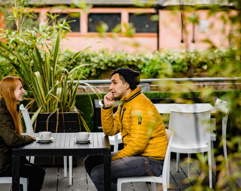 Man and woman sit at cafe table in discussion.